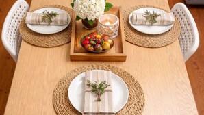 A wooden dining table with woven placemats, white plates, and neatly folded napkins. - Above-Ground · Sun-Filled · Not a Basement · Your Own Private Entrance (Brampton)