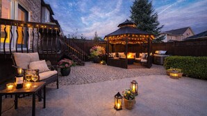 Eine Außenpatio mit einem Pavillon, einer Sitzecke und einem Feuerkorb.