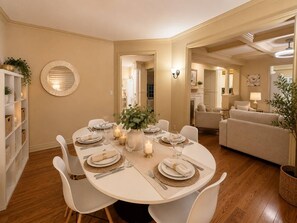 A dining area with a round table set for four, surrounded by white chairs. - Poolside 4BR by Canterra Stays · Sleeps 12 (Brampton)