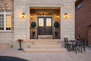 A building entrance with a double door, steps leading up to it, and two round topiary decorations. - Poolside 4BR by Canterra Stays · Sleeps 12 (Brampton)