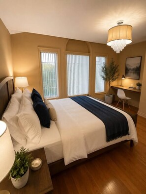 A hotel room with a large bed, bedside lamps, a desk, and a chandelier. - Poolside 4BR by Canterra Stays · Sleeps 12 (Brampton)