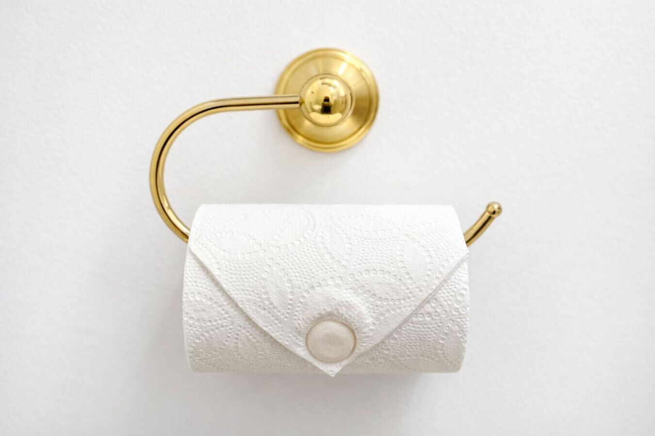 A toilet paper roll mounted on a wall with a brass holder.