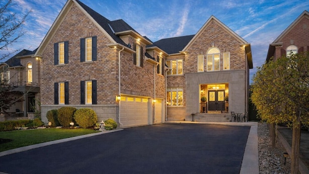 Une grande maison à deux étages, dotée d’un garage, d’une pelouse bien entretenue et d’une allée.