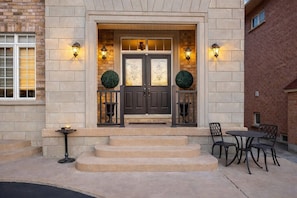 A building entrance with a double door, steps leading up to it, and two round topiary decorations. - 4BR · 2 Suites by Canterra Stays · Sleeps 8 (Brampton)