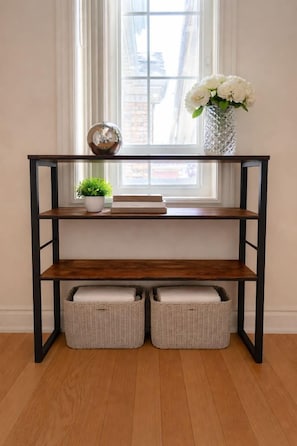 Een houten console tafel met twee rieten manden, een bloempot en een vaas met bloemen.