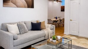 A modern living room with a grey sofa, a glass coffee table, and a grey rug. - Two Independent Suites · Two Entrances · Sleeps 8 · Fireplace + Sun-Filled Upper Unit (Brampton)