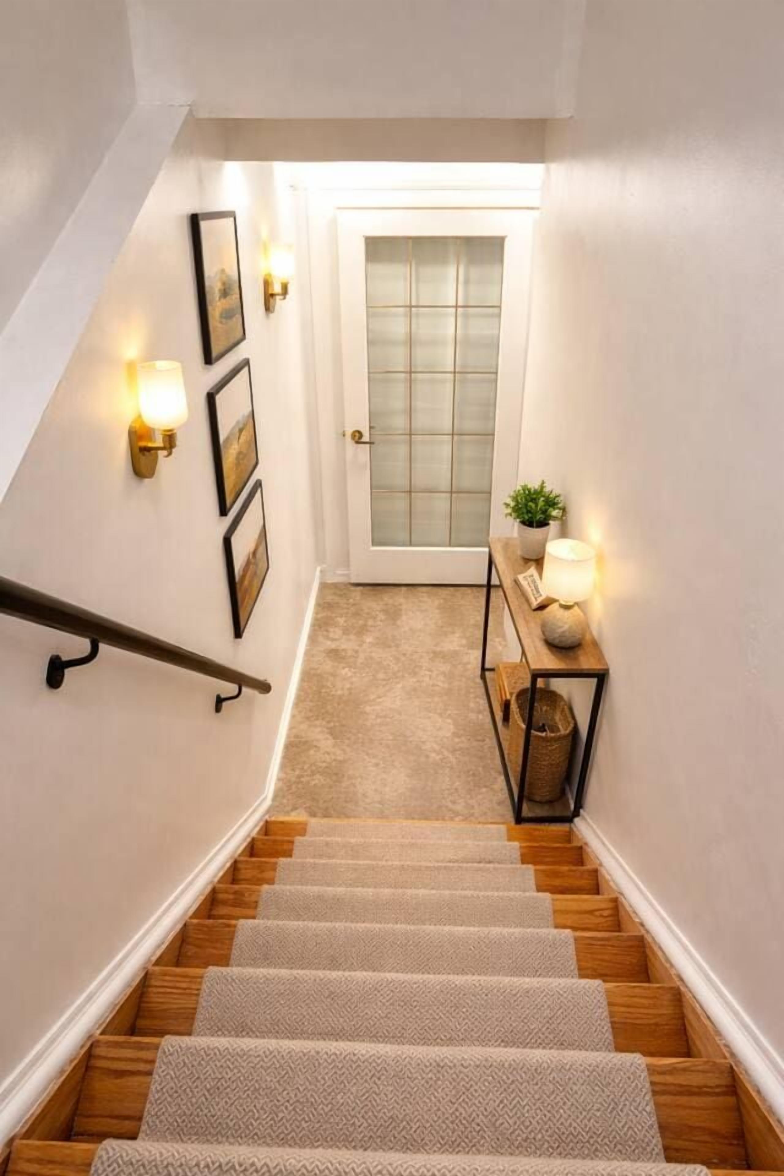 A staircase with a handrail, carpeted steps, a door with frosted glass panels, and wall-mounted light fixtures.