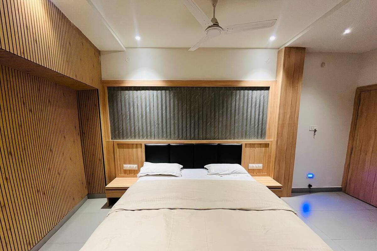 Ein modernes Schlafzimmer mit einem Bett, Holzwandverkleidung, einem Deckenventilator und einem Nachttisch.