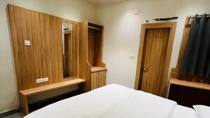 Una camera d'albergo con un letto, un armadio in legno e uno specchio.