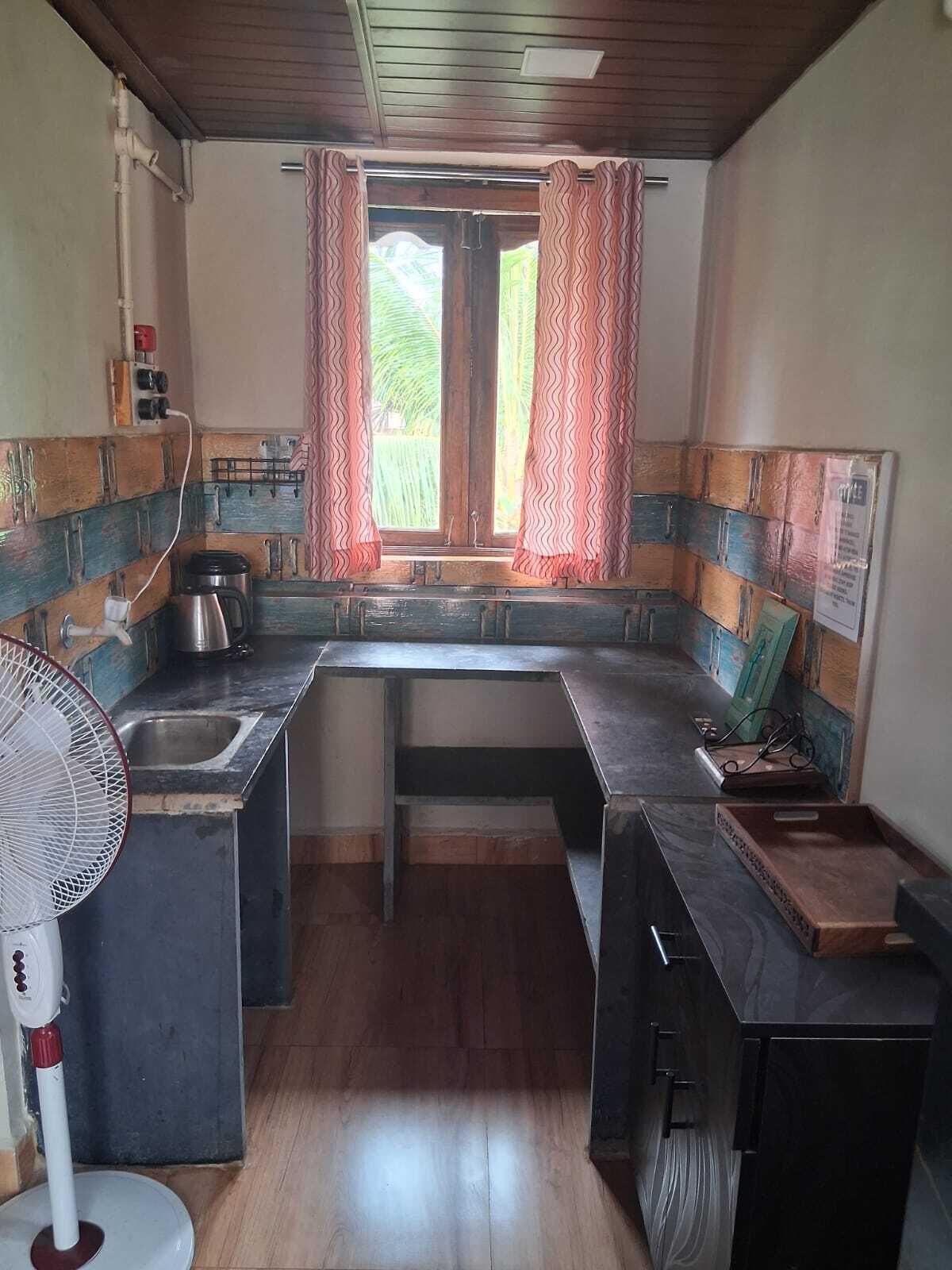A kitchen with a wooden countertop, a sink, a fan, and a window with curtains.