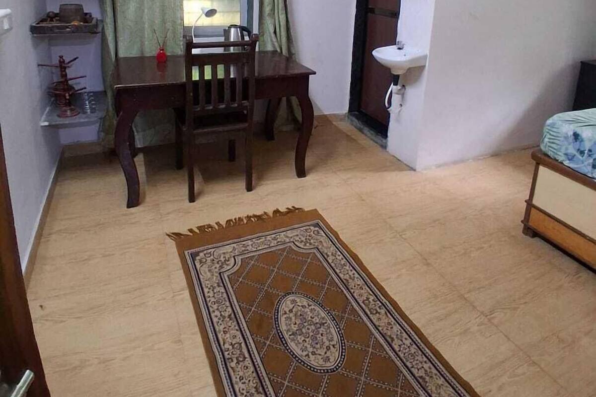 Un espacio habitable compacto con una mesa de comedor, un ventilador de techo, un lavamanos pequeño y una ventana con cortinas.