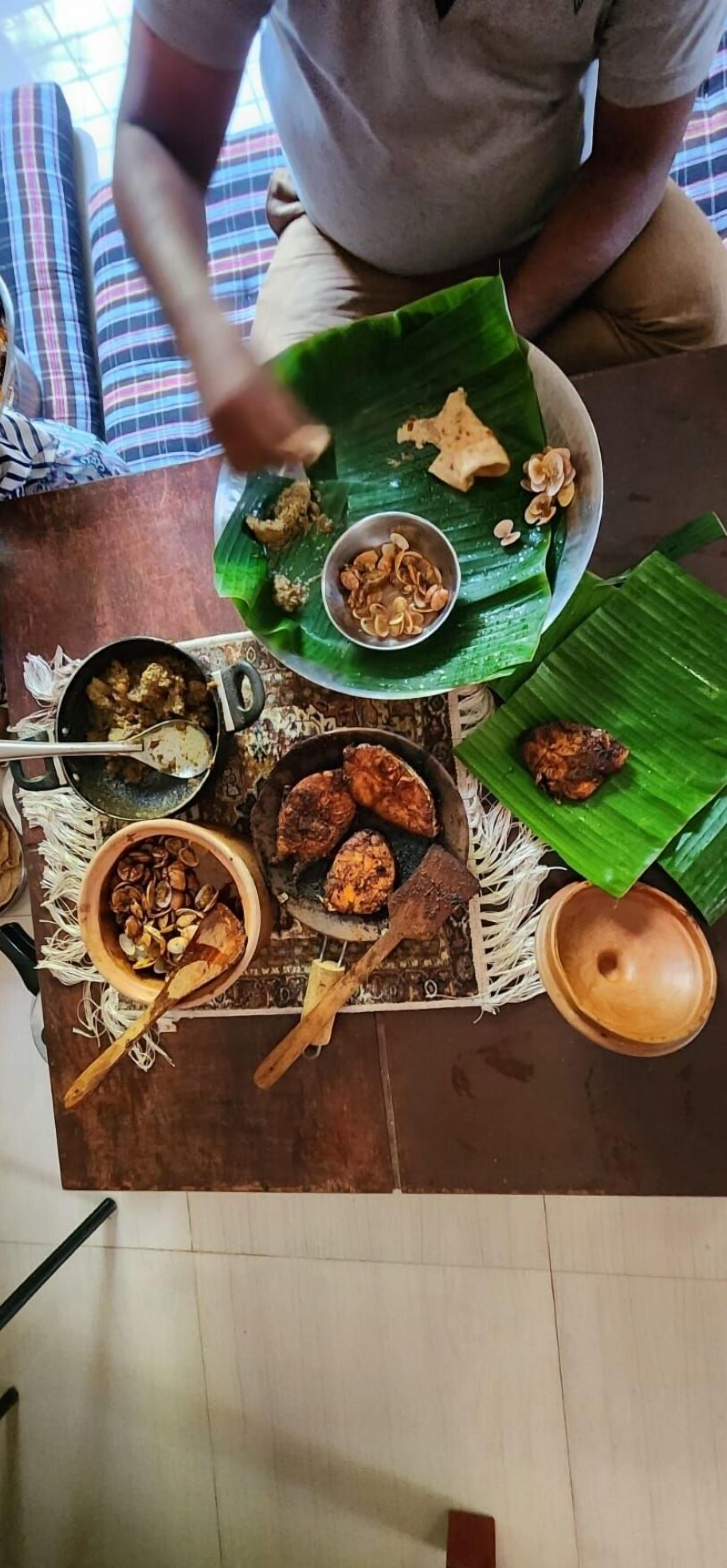 Una mesa de comedor con diversos platos, incluyendo alimentos fritos y un cuenco de nueces, sobre un tapete con una hoja verde.