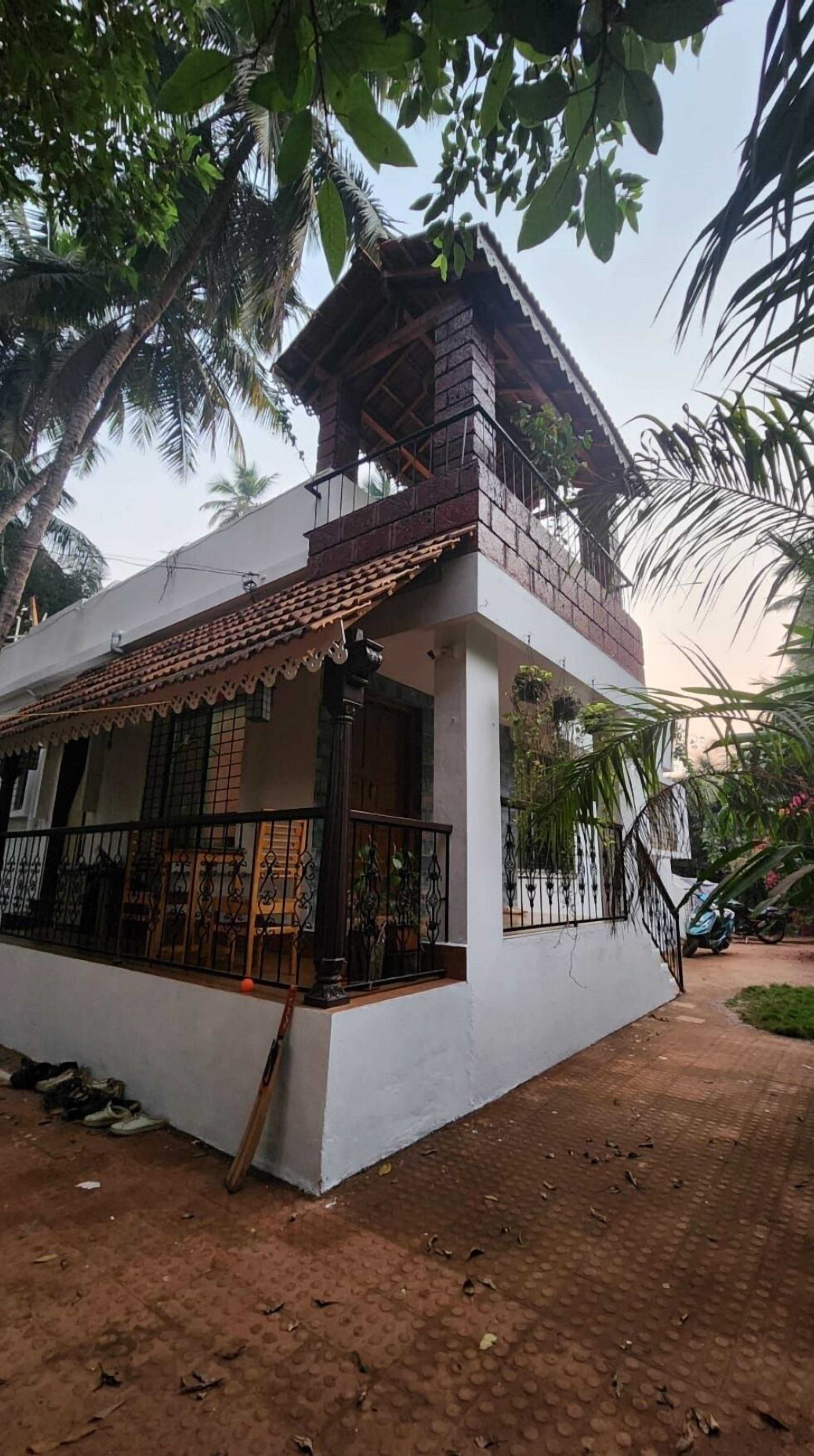 A two-story building with a balcony, surrounded by palm trees.