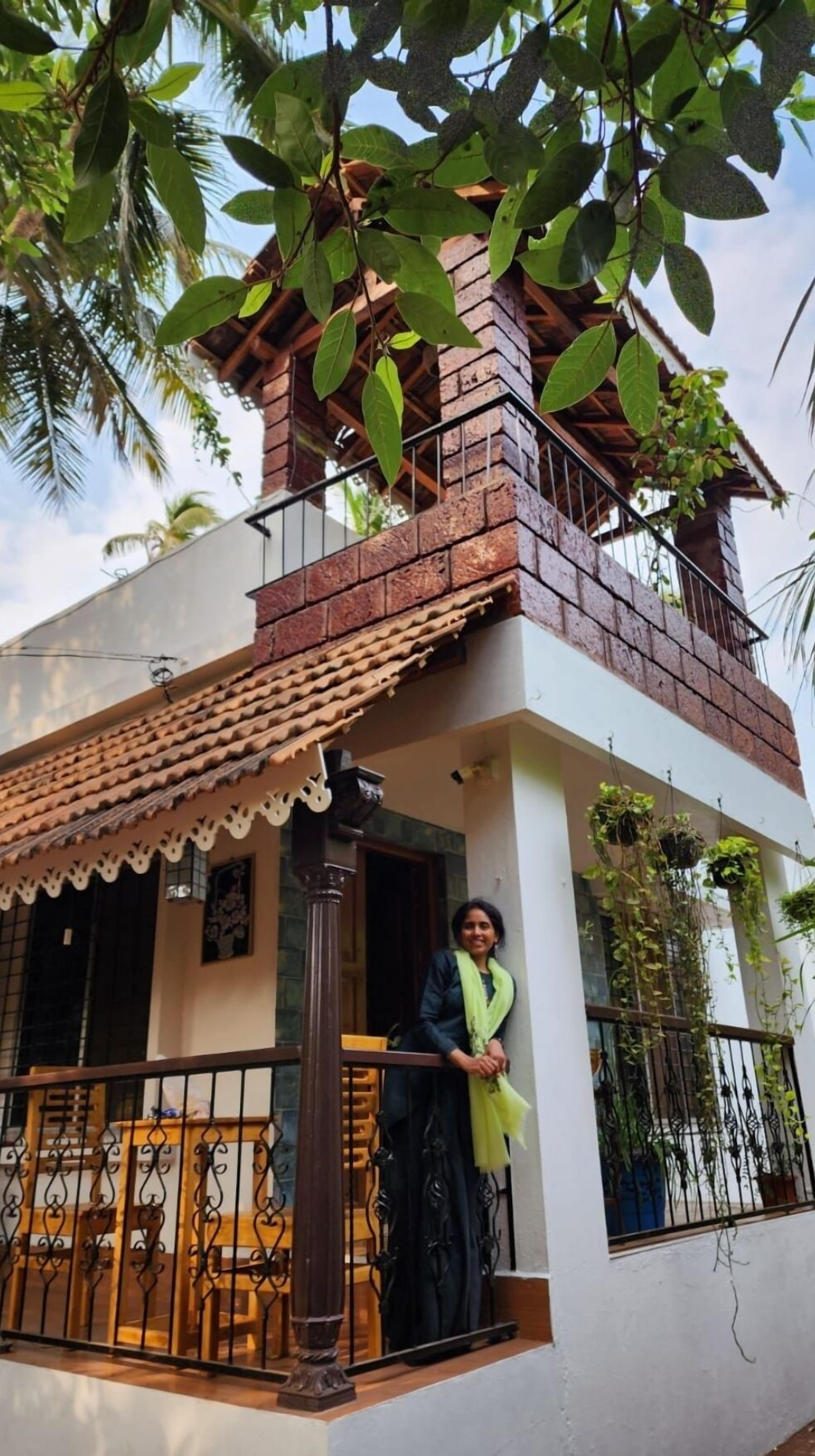 A two-story house with a balcony, a tiled roof, and a brick chimney.