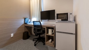 Hotellihuone, jossa on työpöytä, taulutelevisio, mikroaaltouuni, kahvinkeitin ja minijääkaappi.