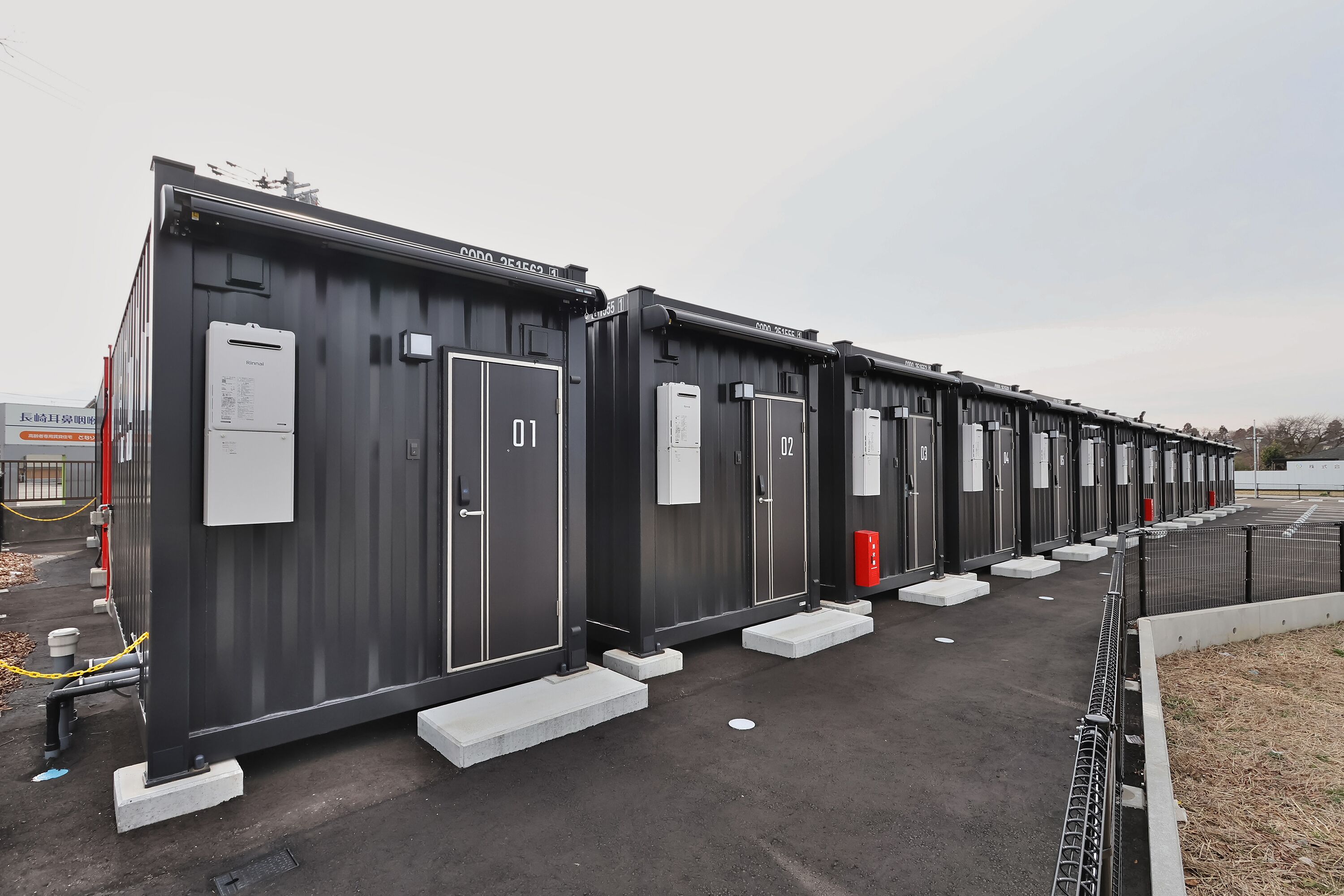 A row of industrial-style buildings with numbered doors, likely serving as storage or utility units.