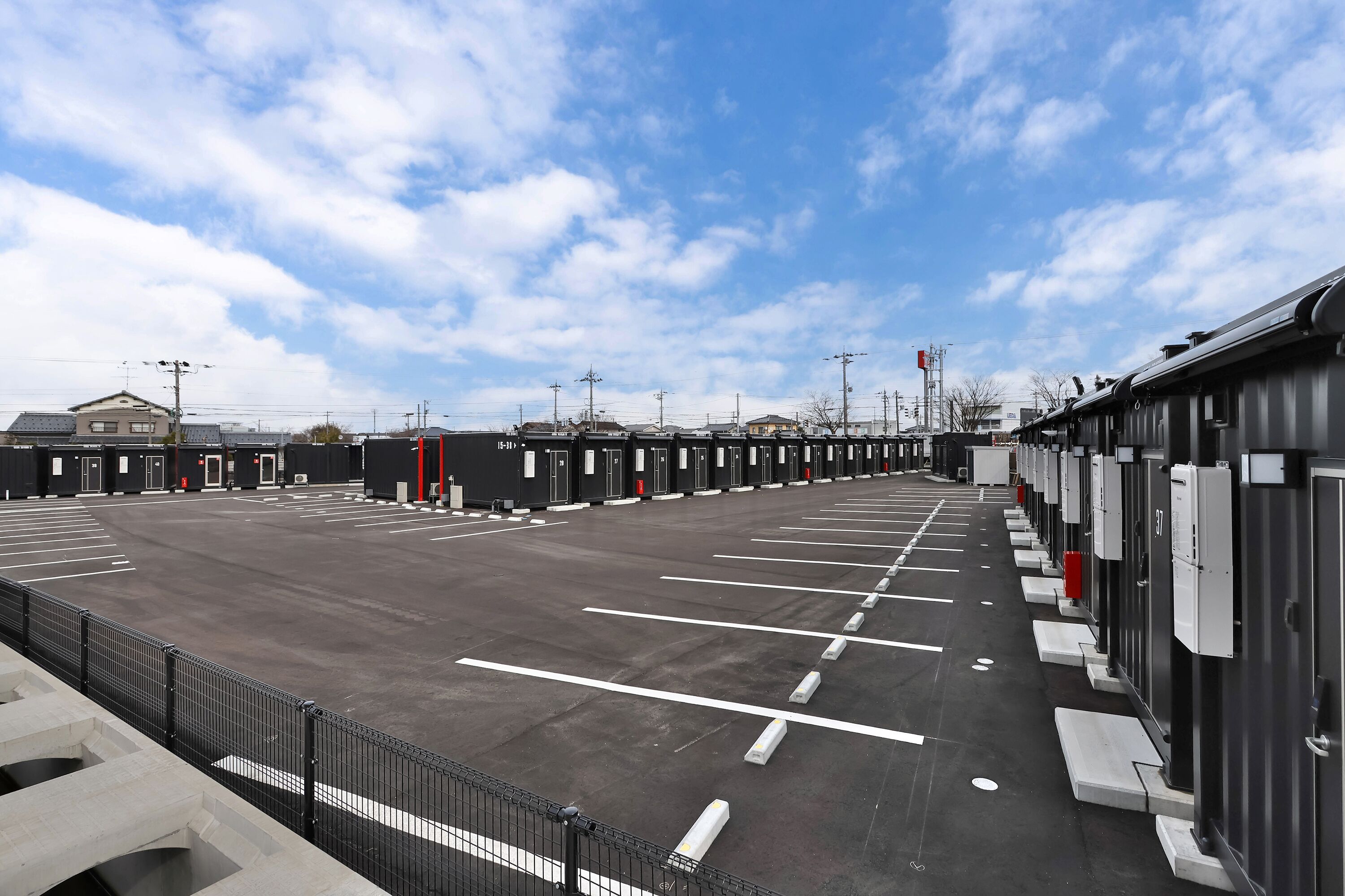 A parking lot with multiple rows of parking spaces and a row of portable toilets.