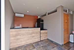A reception area with a wooden reception desk, a wall-mounted air conditioner, and a closed door labeled "Staff Only".