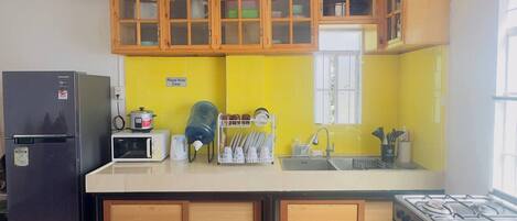 Una cocina con armarios de madera, un refrigerador, un microondas, una estufa y un fregadero.