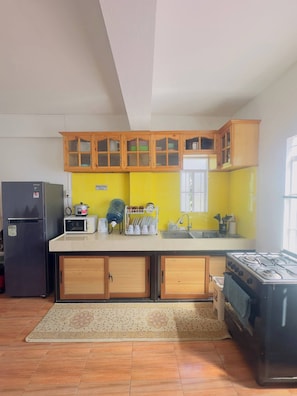 A kitchen with wooden cabinets, a refrigerator, a microwave, a stove, and a sink. - Zen Ridge Stay Baguio City (Baguio)