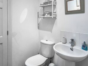 Een kleine, witte badkamer met toilet, wastafel en spiegel.