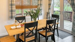 A dining area with a wooden table, black chairs, a vase with flowers, and a bottle of wine. - 2 bedroom accommodation in Rock (Rock)