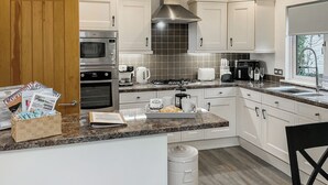 A modern kitchen with white cabinets, stainless steel appliances, a granite countertop, and a window providing natural light. - 2 bedroom accommodation in Rock (Rock)