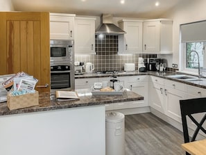 A modern kitchen with white cabinets, stainless steel appliances, a granite countertop, and a window providing natural light. - 2 bedroom accommodation in Rock (Rock)