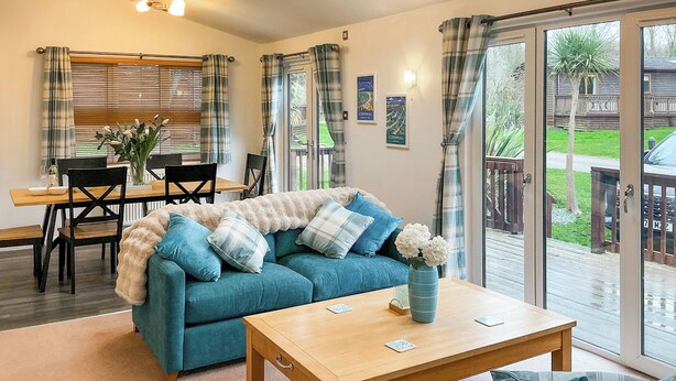 A cozy living room with a blue sofa, a wooden coffee table, and a dining area with a table and chairs. - 2 bedroom accommodation in Rock (Rock)