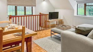 Een gezellige woonkamer met een eethoek, een televisie en uitzicht op de omgeving.