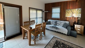 A living room with a wooden dining table, two chairs, a sofa, and a TV. - Cabin One- Sauna, pet-friendly, adults only (Lowanna)
