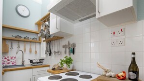 A modern kitchen with white cabinets, a stove, a wooden countertop, and various kitchen utensils. - 1 bedroom accommodation in Paignton (Paignton)