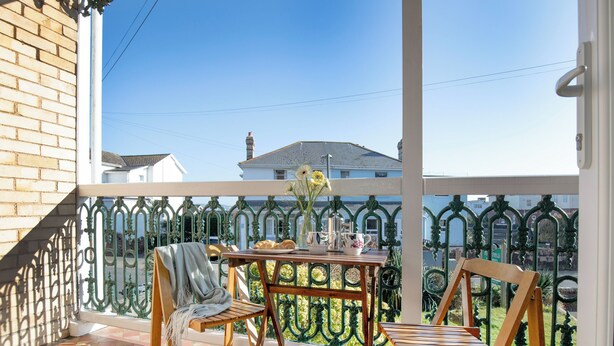 A balcony with a table, chairs, and a vase of flowers. - 1 bedroom accommodation in Paignton (Paignton)