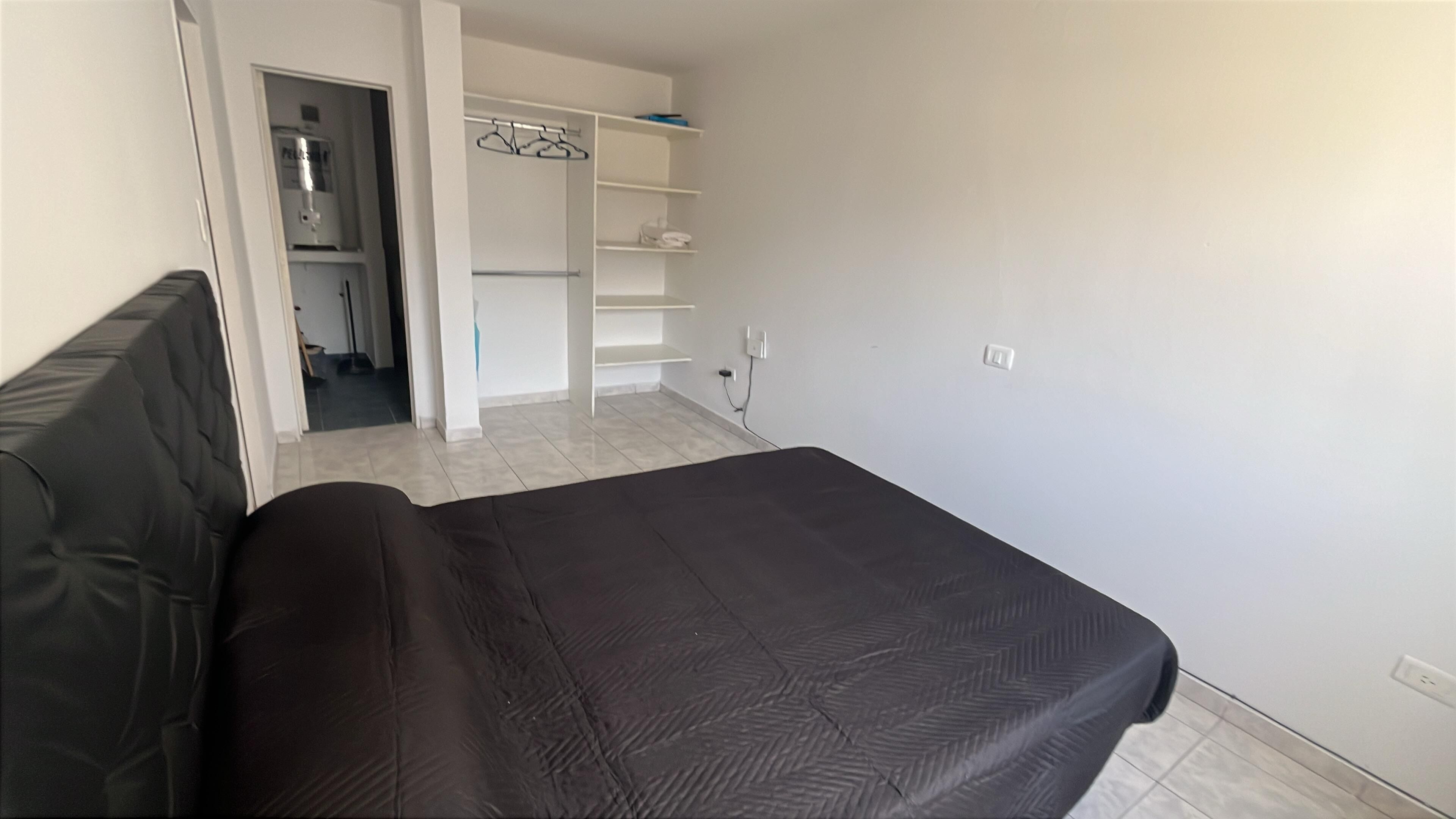 A bedroom with a bed, a wardrobe, and a bathroom visible through an open door.