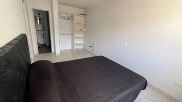 A bedroom with a bed, a wardrobe, and a bathroom visible through an open door.
