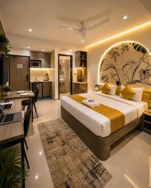 A modern hotel room with a bed, bedside table, desk, and chair.