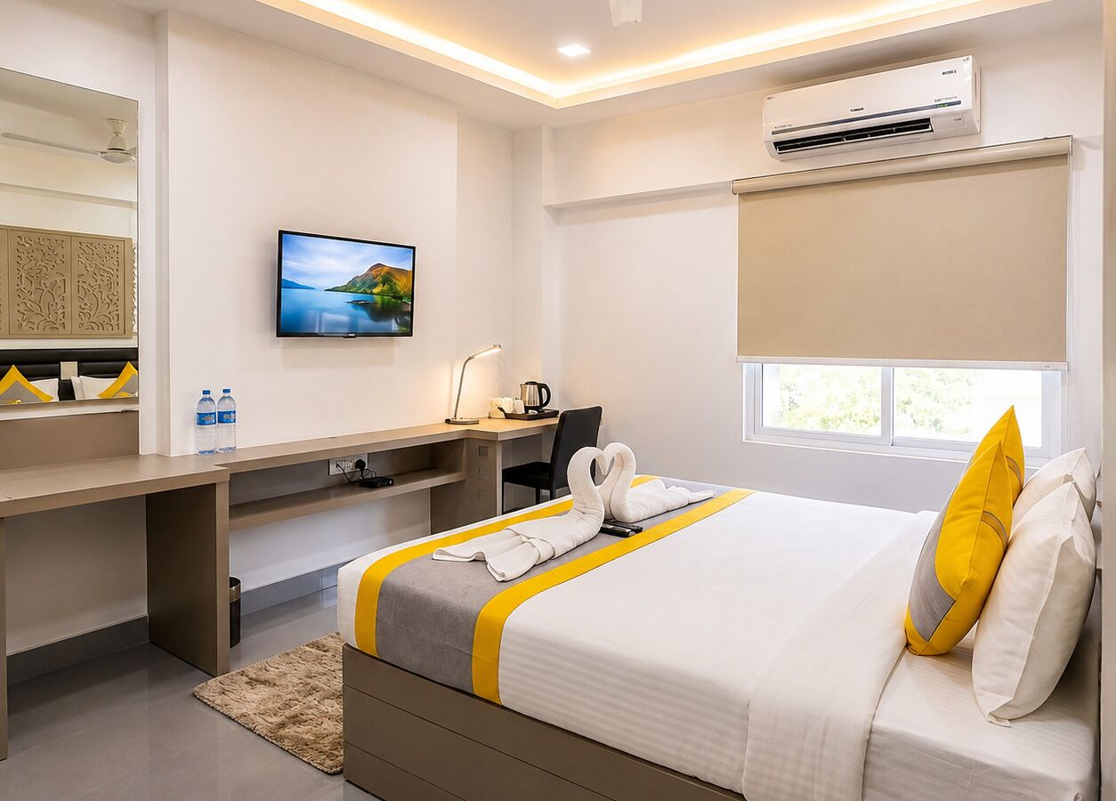 Quarto de hotel com cama, escrivaninha e ar condicionado.