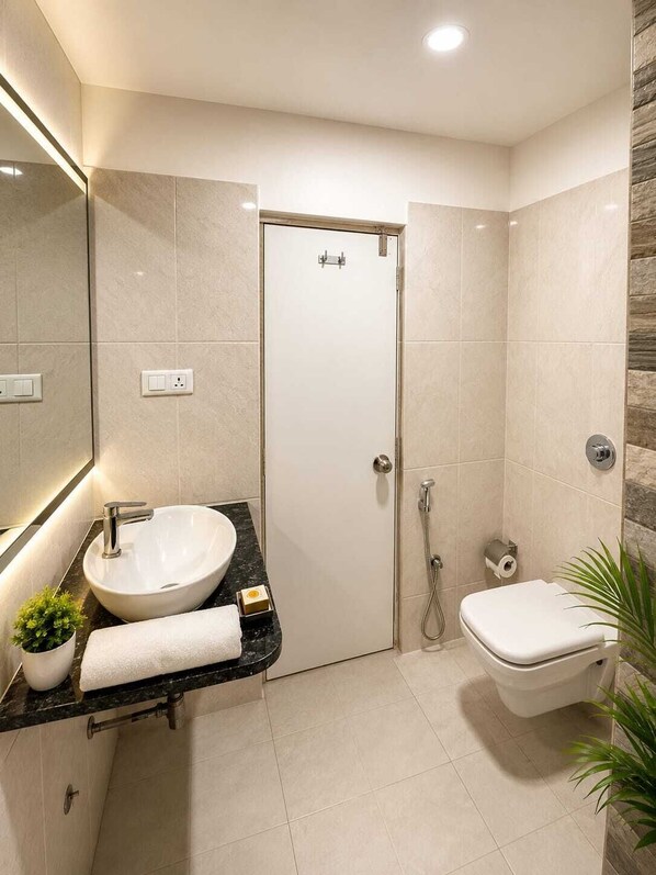 A modern bathroom with a white sink, a toilet, and a shower. - La Riviera Suites (Hyderabad)