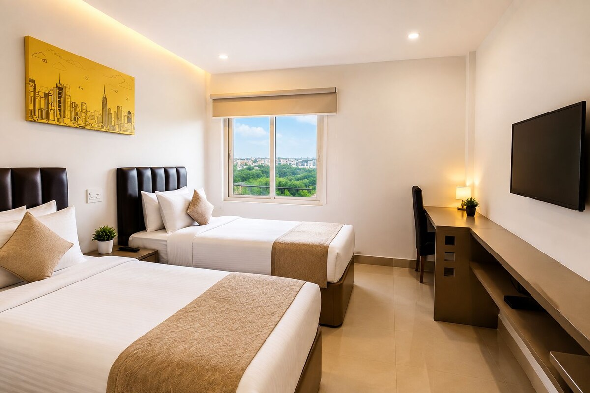 A hotel room with two beds, a desk, a TV, and a cityscape painting.