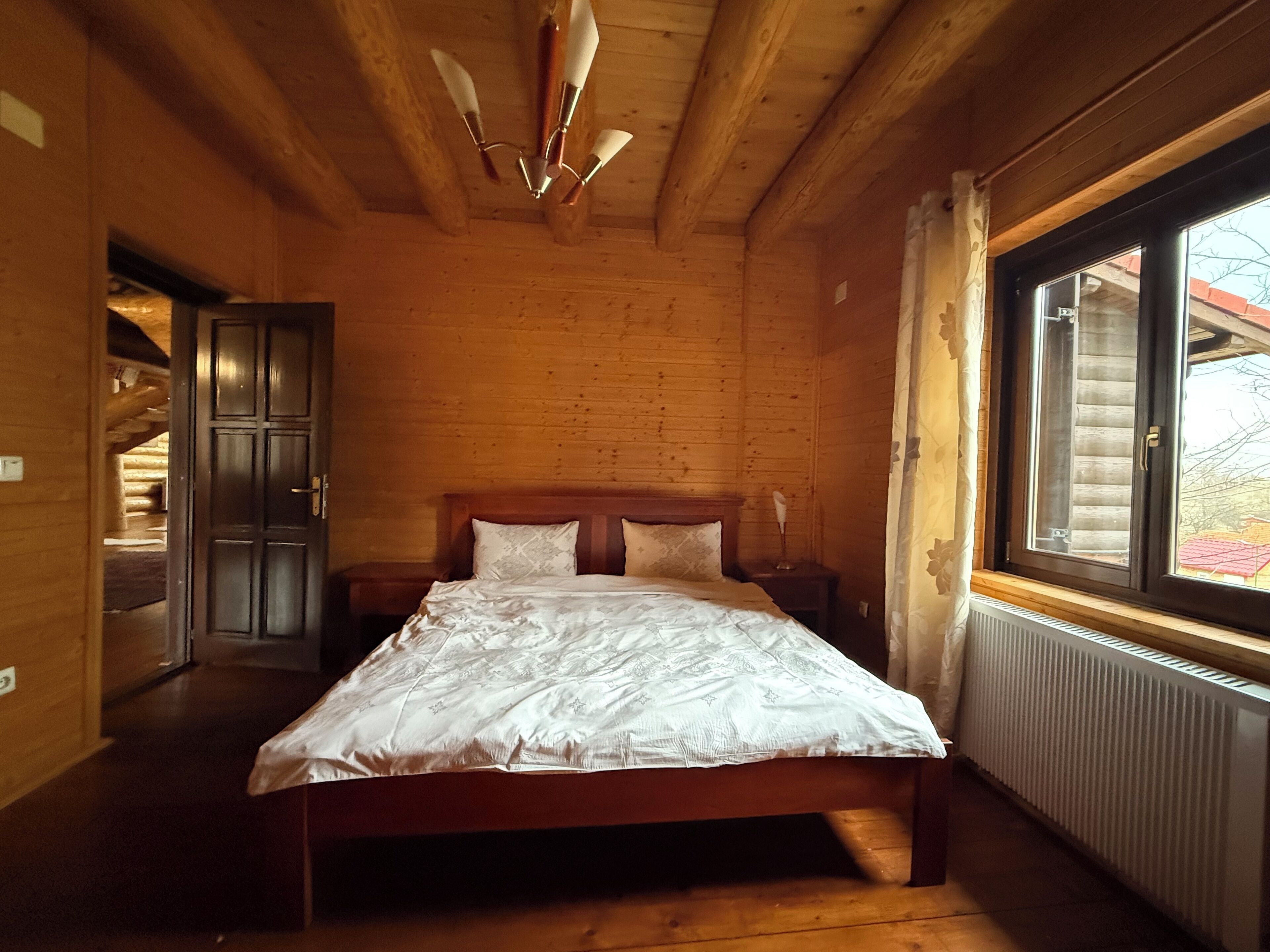 Une chambre dans une cabane en bois, avec un lit, une fenêtre et un ventilateur de plafond.