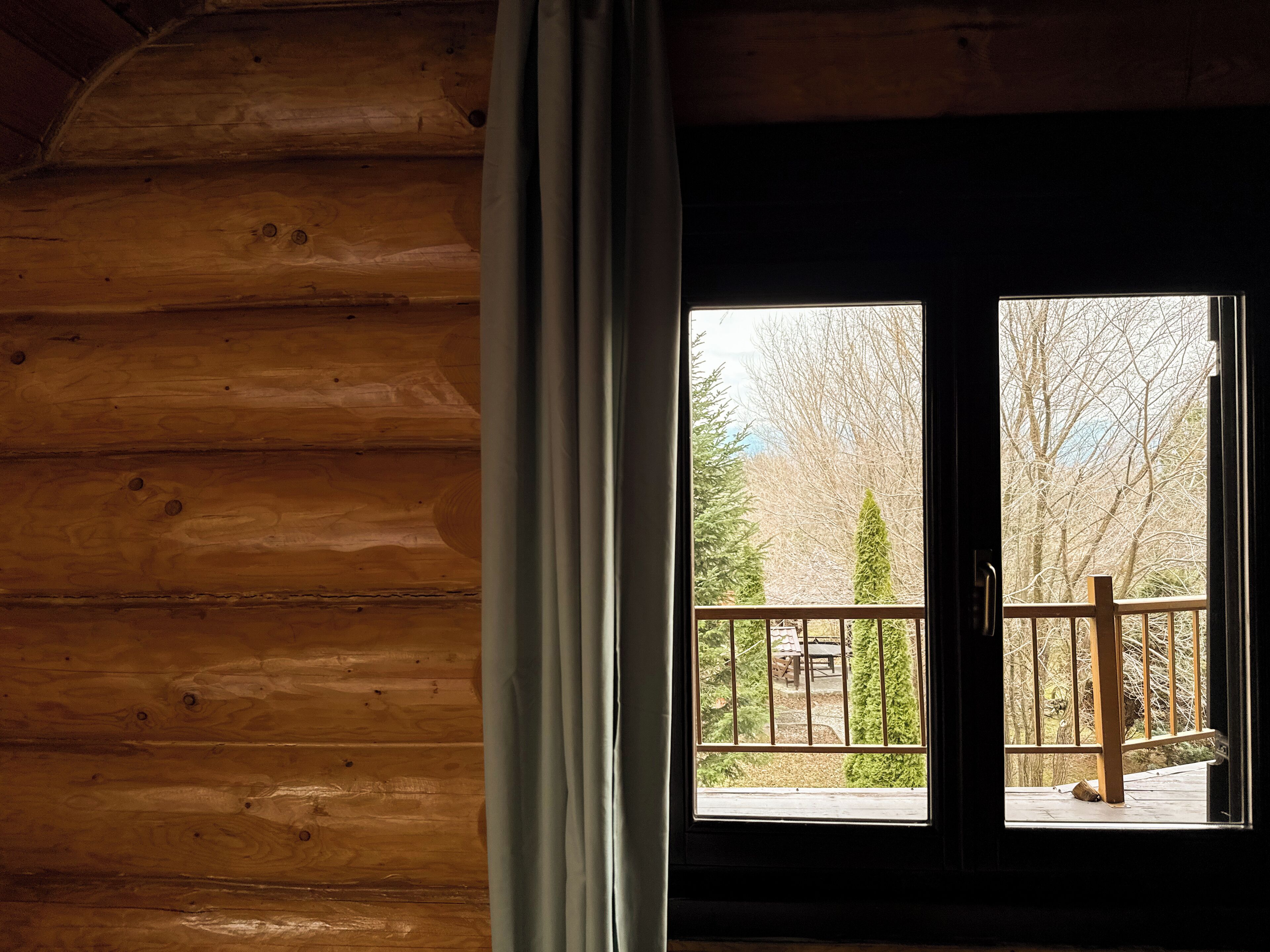 A wooden cabin interior with a large window and a curtain.