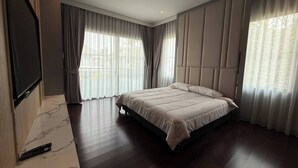 Un dormitorio moderno con una cama grande, un televisor de pantalla plana montado en la pared y un piso de baldosas de mármol.