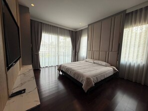 A modern bedroom with a large bed, a flat-screen TV mounted on the wall, and a marble-tiled floor. - House near Suvarnabhumi Airport (Tambon Rachathewa)