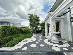 A pathway leading to a building with a fountain and a statue. - House near Suvarnabhumi Airport (Tambon Rachathewa)