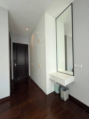 A hallway with a dark wooden floor, white walls, a large mirror, and a white console table. - House near Suvarnabhumi Airport (Tambon Rachathewa)