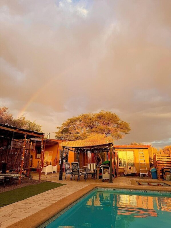 Un patio trasero con piscina, muebles de exterior y un árbol.