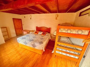 Ein Schlafzimmer mit einem Holzstockbett, einem Einzelbett, einem Schreibtisch und einem Stuhl.