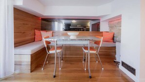 A modern dining area with a glass table, metal chairs, and a wooden bench with orange cushions. - The Funky Den on Warwick (Hobart City)