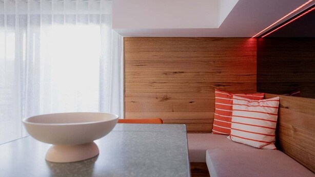 A modern interior with a wooden headboard, a white bowl on a table, and striped pillows. - The Funky Den on Warwick (Hobart City)