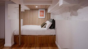 A bedroom with a bed against a wall, a wooden floor, and a framed picture above the bed. - The Funky Den on Warwick (Hobart City)